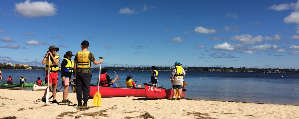 Scouts by the Swan River wearing lifejackets and getting into canoes