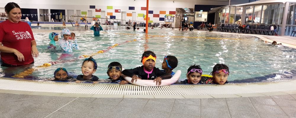 Multicultural kids along the edge of the pool with their Swim Instructor at Cannington Leisureplex