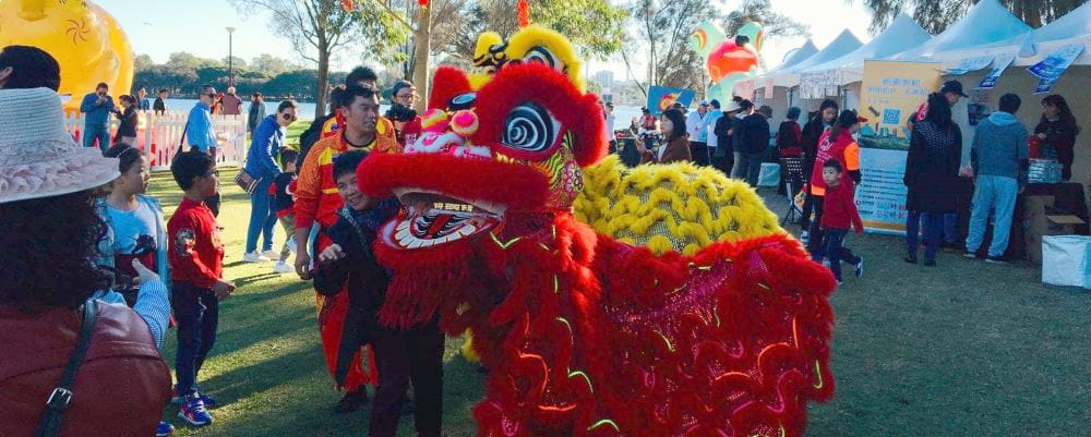 A red Chinese dragon entertaining a crowd at the Chung Wah Festival
