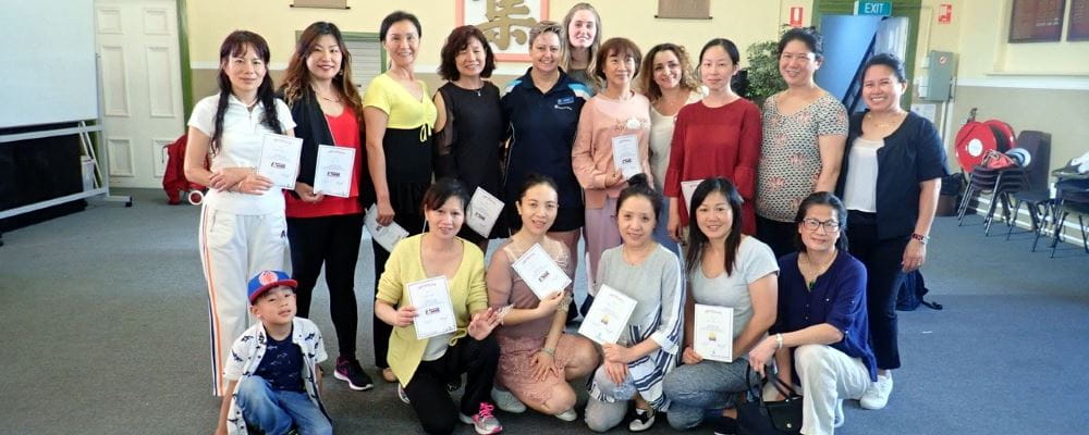 A group of Chinese women with their trainer holding their certificates after completing a Heart Beat Club course