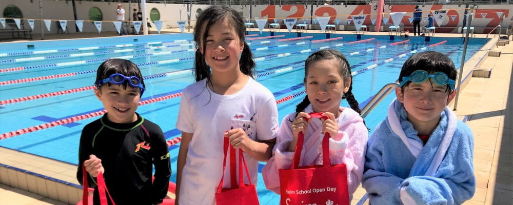 Four children stadning by the pool at Churchlands with their Swim and Survive packs