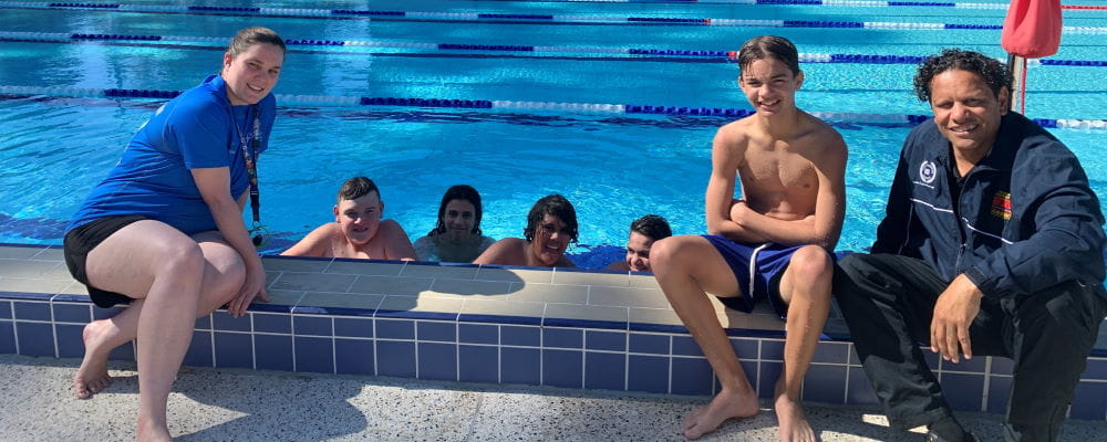 Five Aboriginal boys with their swim instructor and teacher by the pool at Armadale Aquatic Centre