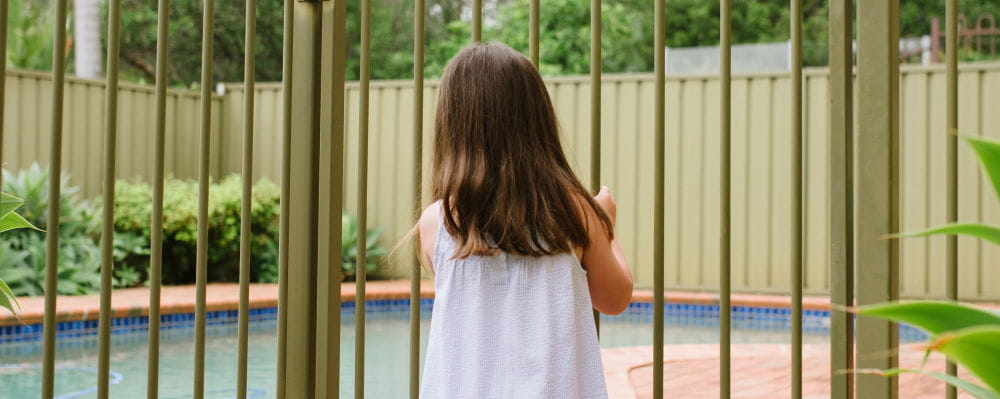 I little girl standing at a pool gate