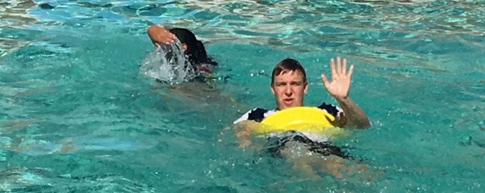 Teenage boy waving in the pool