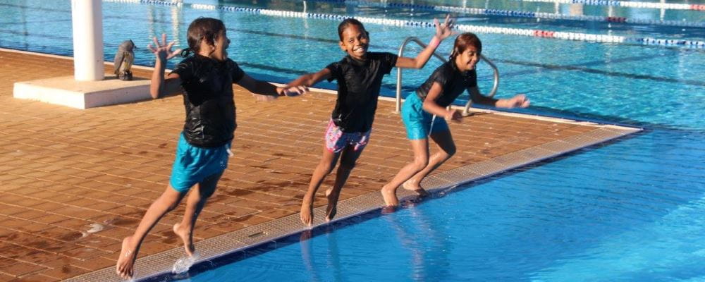 three Aboriginal girls jumping into the pool