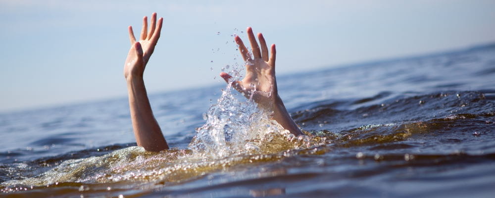 A person underwater with their hands raised above the surface