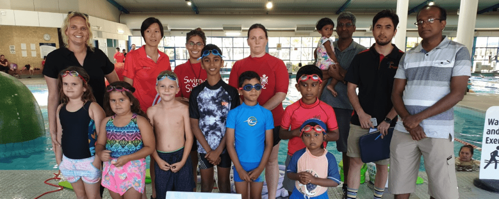 Children, parents and swim instructors by the pool