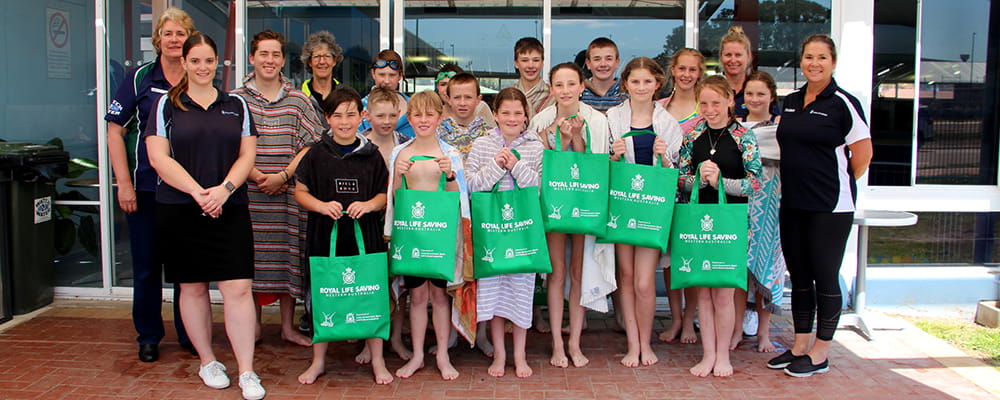 Kids and coaches at the Bay of Isles leisure centre holding junior lifeguard club bags after swimming event