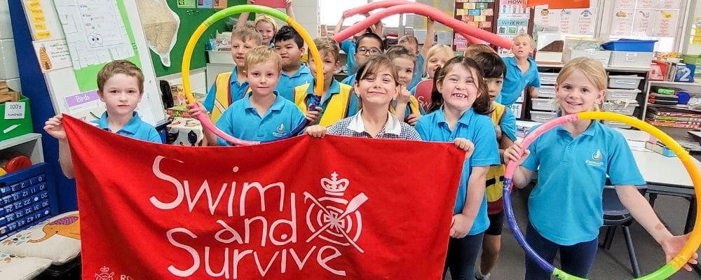 Exmouth children in their classroom holding a Swim and Survive banner