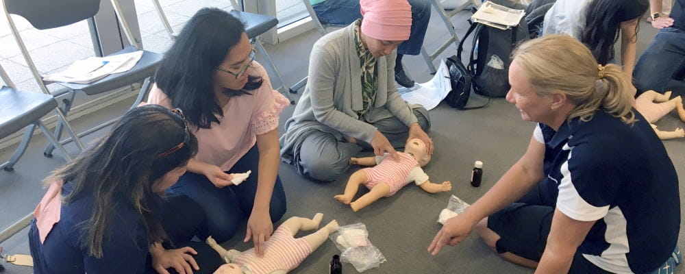 Women practising infant CPR on a manikin with a Royal Life Saving Trainer