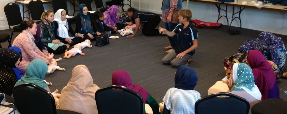 A group of parents and carers in a circle around a heart beat club trainer