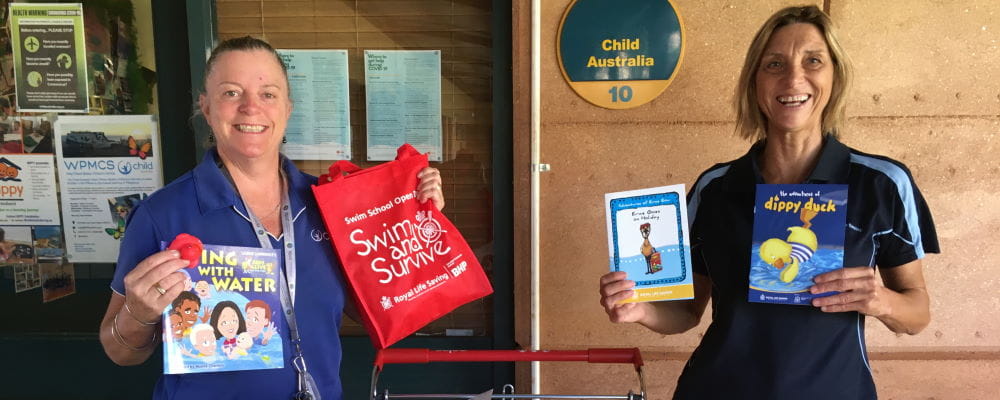 Two women holding Royal Life Saving books and activity bags