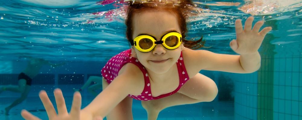 image of girl underwater in a pool looking at camera