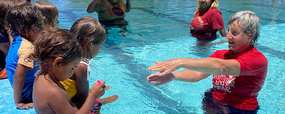 Aboriginal children on the pool edge with instructor Deb Gill in the water