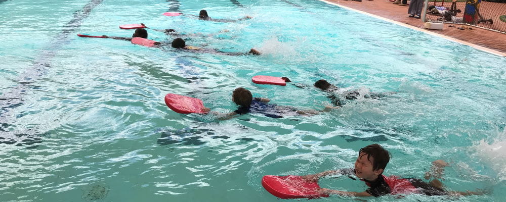 Children swimming with kickboards at Jigalong Remote Aboriginal Swimming Pool