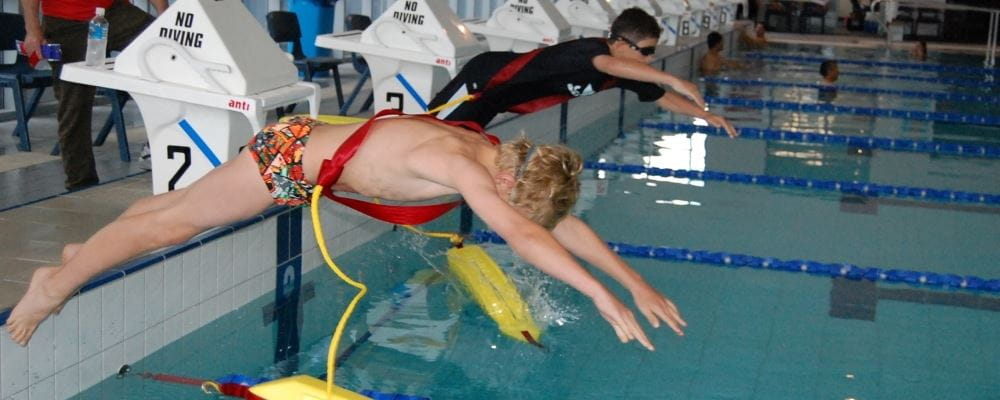 Image of young boy diving into pool with rescue tube