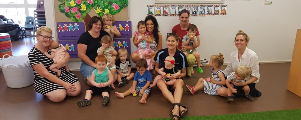 Mums with babies siting on the floor of a community centre with their Royal Life Saving trainer