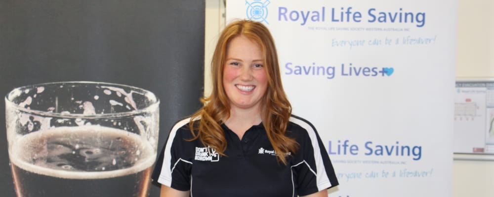 Image of Kymberley Doig standing in front of Don't Drink and Drown and Royal Life Saving Banners