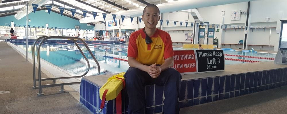 Image of Lee Tran with his lifeguard gear by the pool at Ballajura Leisure Centre