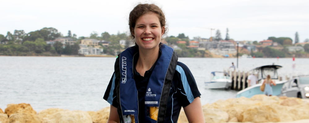 A woman wearing a lifejacket while standing by a river