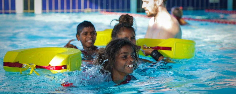 Aboriginal children in the pool pulling rescue tubes
