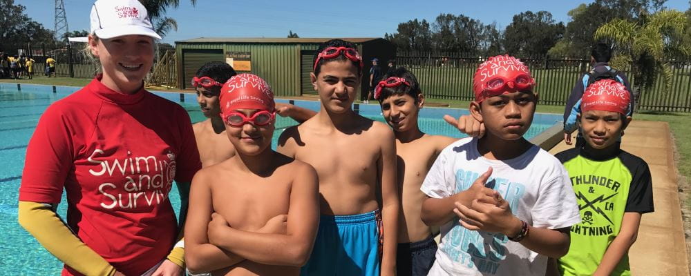 A swim and Survive instructor standing with 6 multicultural boys by the pool at Lynwood