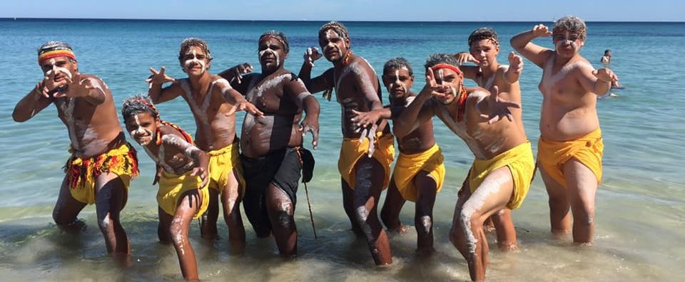 group of young Aboriginal men in traditional dress at the beach