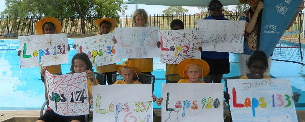 Children hold up signs with number of laps swum