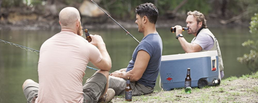 Three men by the river drinking alcohol