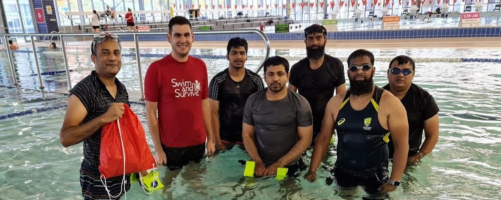 Six multicultural male adults with their swimming instructor