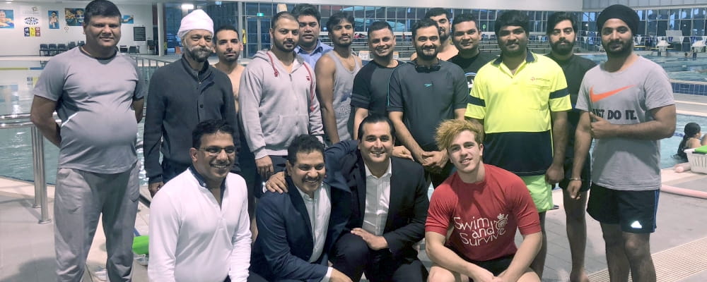 Multicultural men by the pool with Yaz Mubarakai MLA and their swim instructor at Cannington Leisureplex