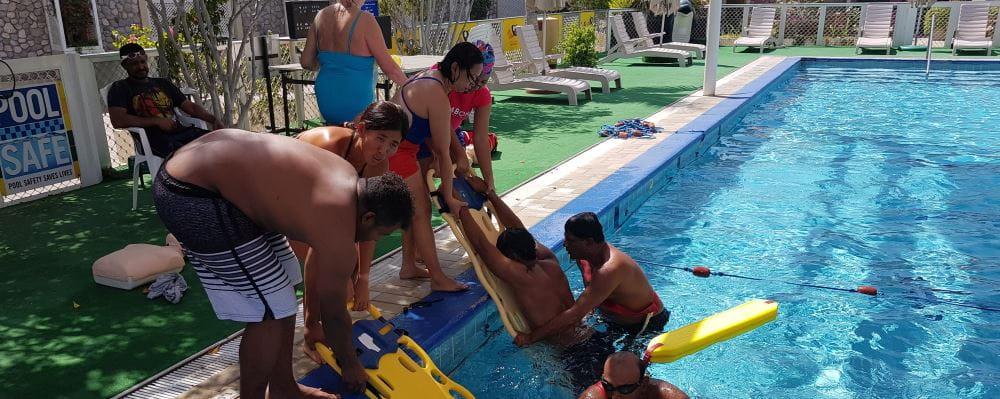 Lifeguards by the pool in Oman using spineboards to remove people from the water