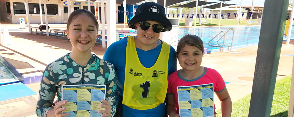 Two students with their swim instructor, Zoe Ross, by the pool at Paraburdoo