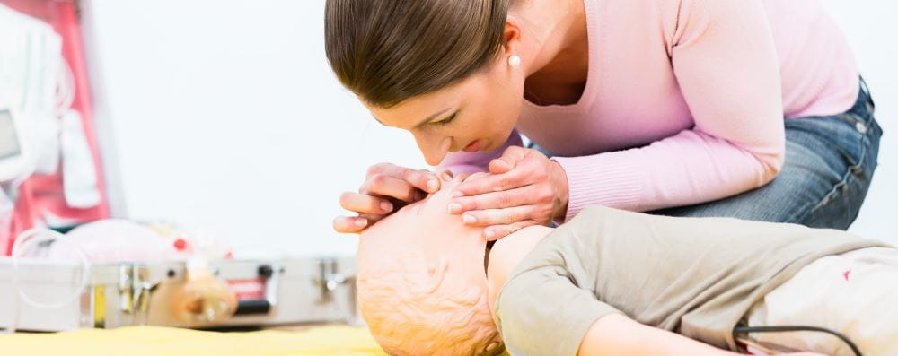 woman practising CPR on child manikin