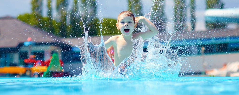 A little boy running into a pool splashing