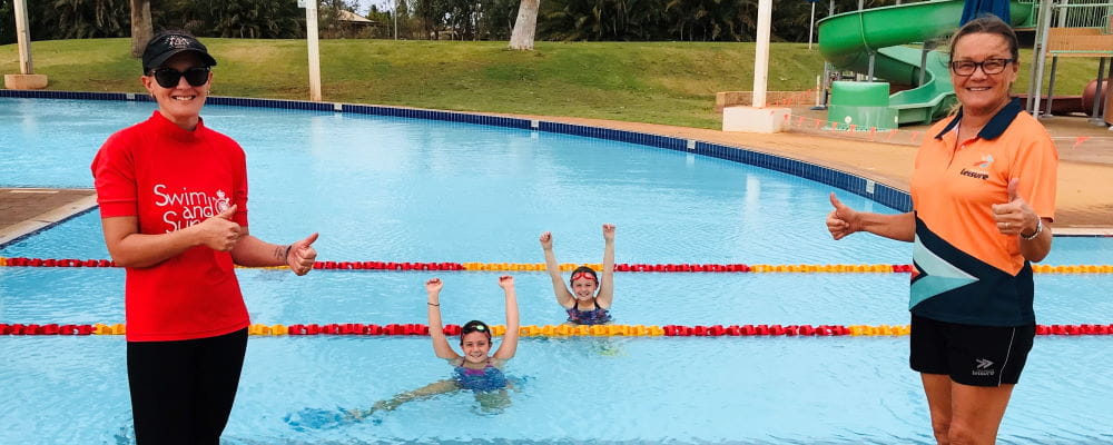 Two swim instructors by the pool with two children in the water at South Hedland Aquatic Centre