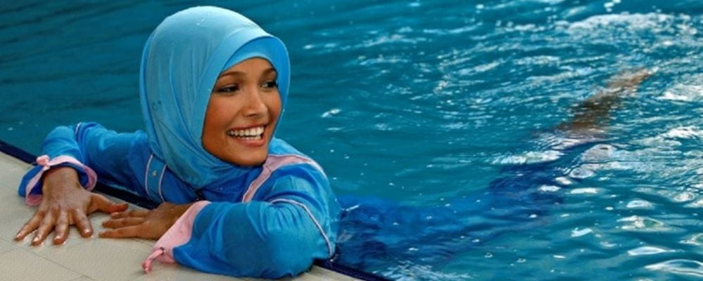 woman wearing muslim clothing swimming in a pool