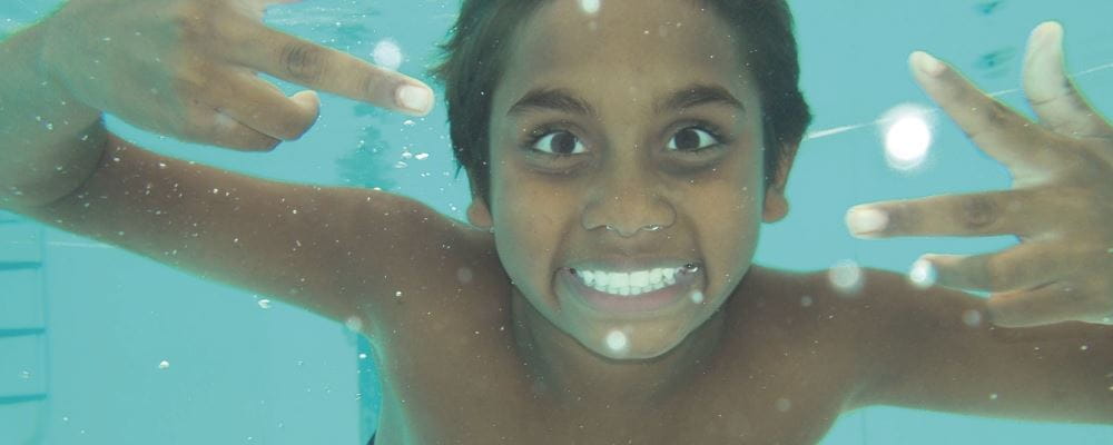 aboriginal water smiling while underwater in pool