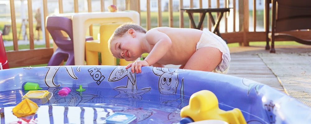 toddler wearing nappy next to inflatable pool