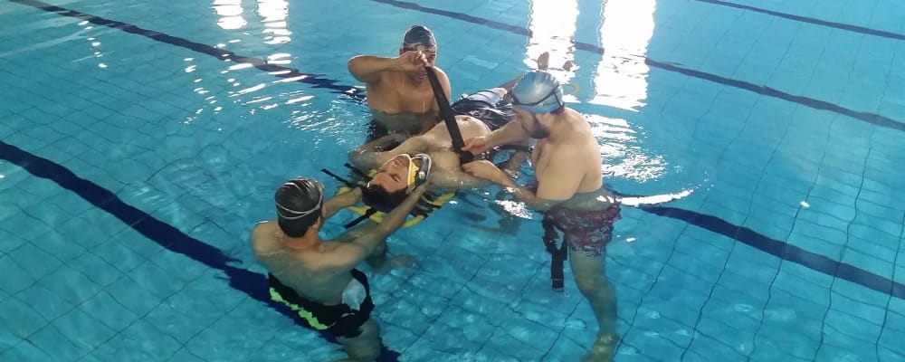 image of 4 Saudi lifeguards practising rescue skills in the pool