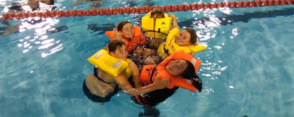 Image of 5 Scouts wearing lifejackets and completing a safety exercise in the pool