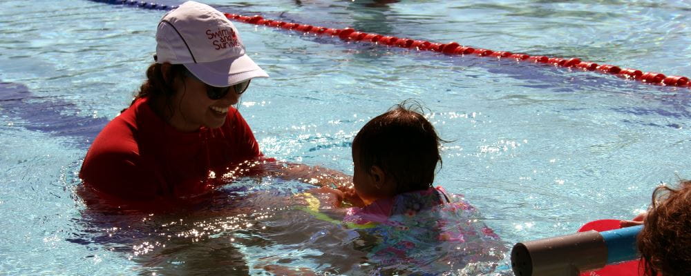 image of a swim instructor with an infant in a swimming class