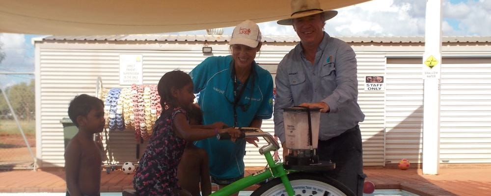 image of children trying out the Smoothie Bike with pool manager Jacqui Forbes and Anthony Holman from EON Foundation