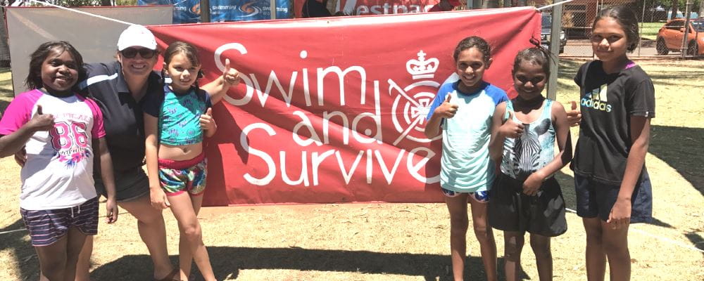 Swim School Coordinator Raelene Leeds with 5 aboriginal girls and a Swim and Survive sign at the Spirit Carnival