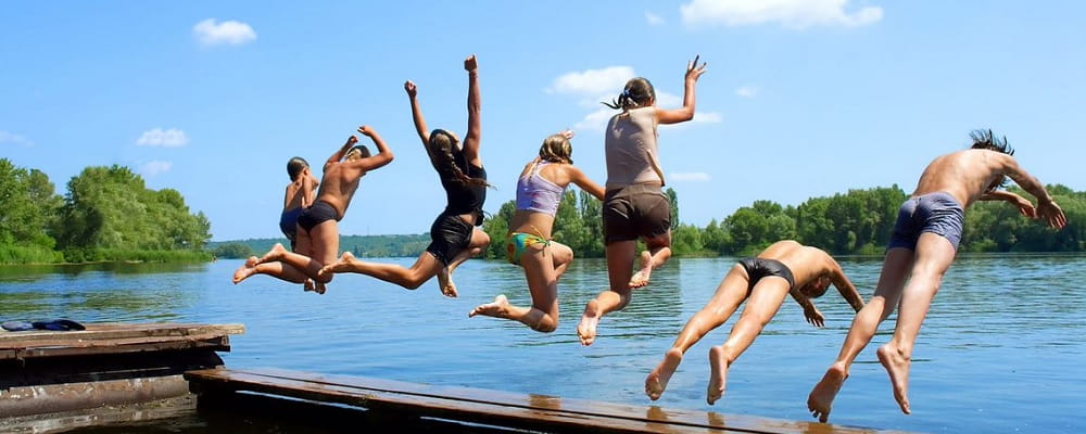 people jumping off a jetty into a river