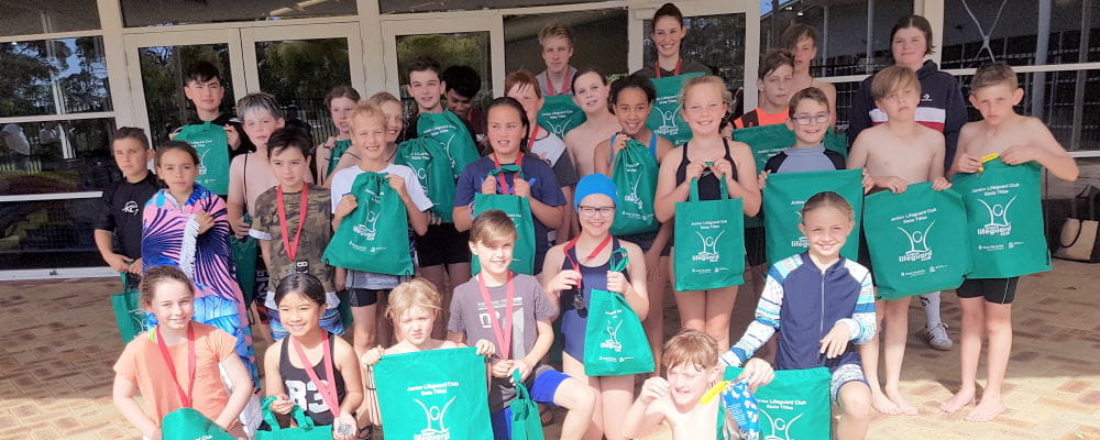 JCL carnival attendees with their coaches, holding green JLC bags outside Swan Active
