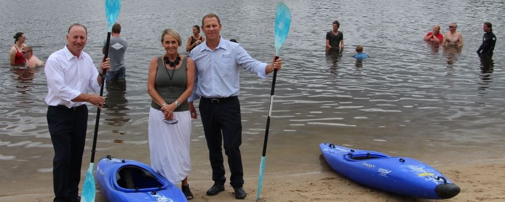 Federal Member for Swan Steve Irons with Caoeing WA CEO Rosalie Evans and Royal Life Saving Society WA CEO Peter Leaversuch by the Swan river at Ascot with Kayaks and oars and children in the river in the background