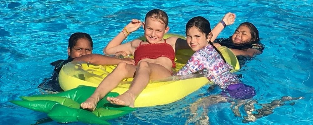 Four girls in the pool on an inflatable pineapple