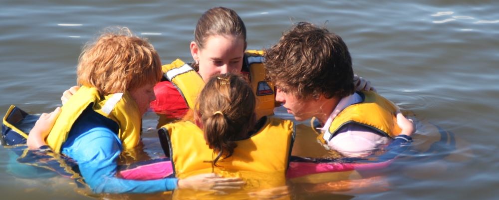 image of 4 children wearing lifejackets and floating in a circle in the river
