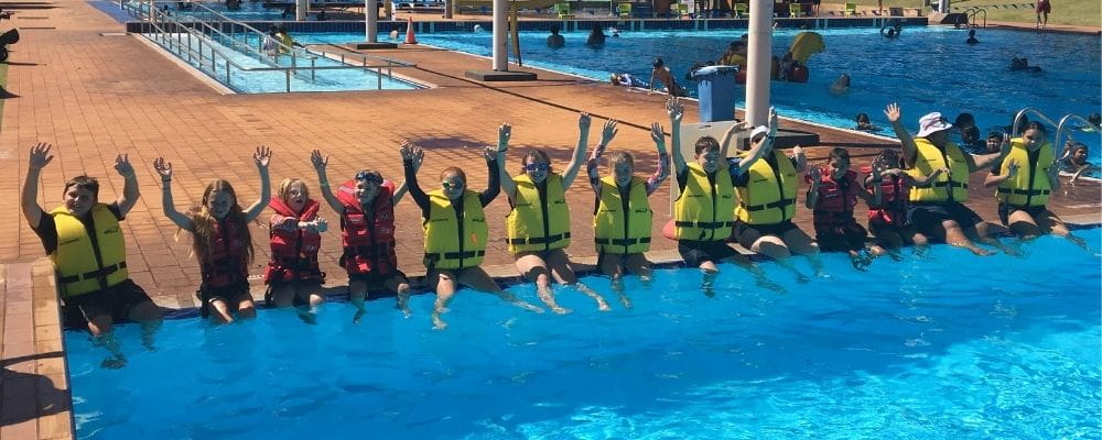 Hedland kids and police wearing lifejackets and sitting on the edge of the pool